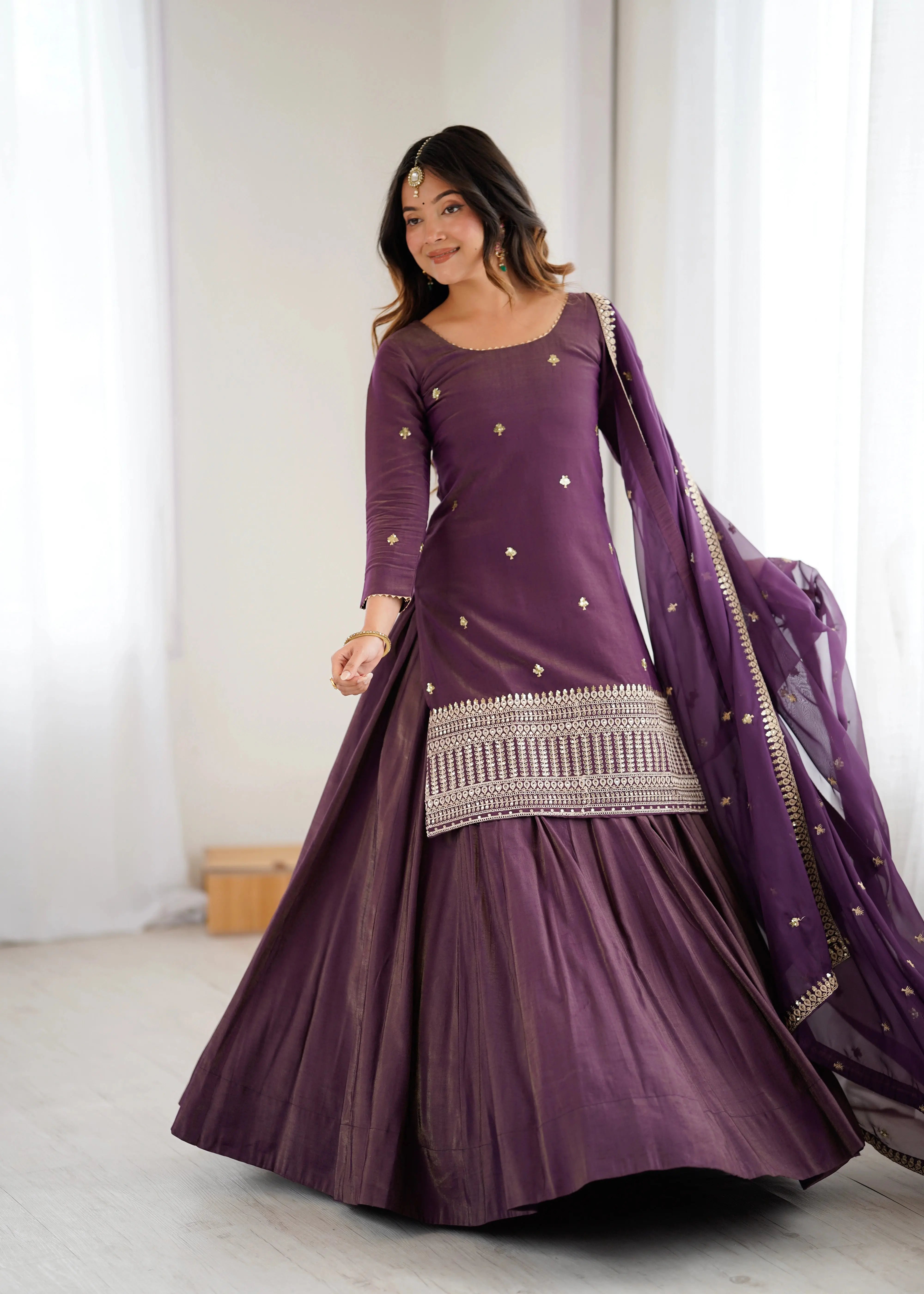 Woman wearing a purple traditional outfit with a matching shawl indoors.